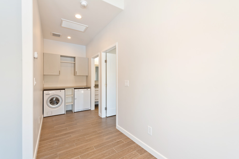 Mid-sized elegant single-wall porcelain tile and brown floor dedicated laundry room photo in San Diego with flat-panel cabinets, beige cabinets, quartz countertops, beige walls and a side-by-side washer/dryer