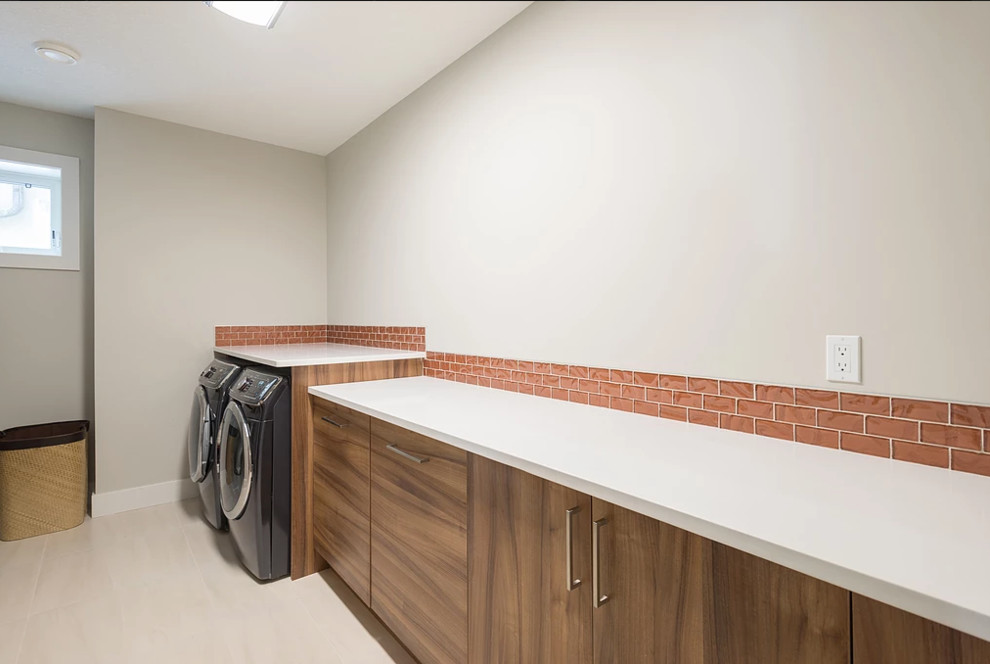 Inspiration for a large traditional single-wall separated utility room in Edmonton with flat-panel cabinets, medium wood cabinets, composite countertops, white walls, a side by side washer and dryer and beige floors.