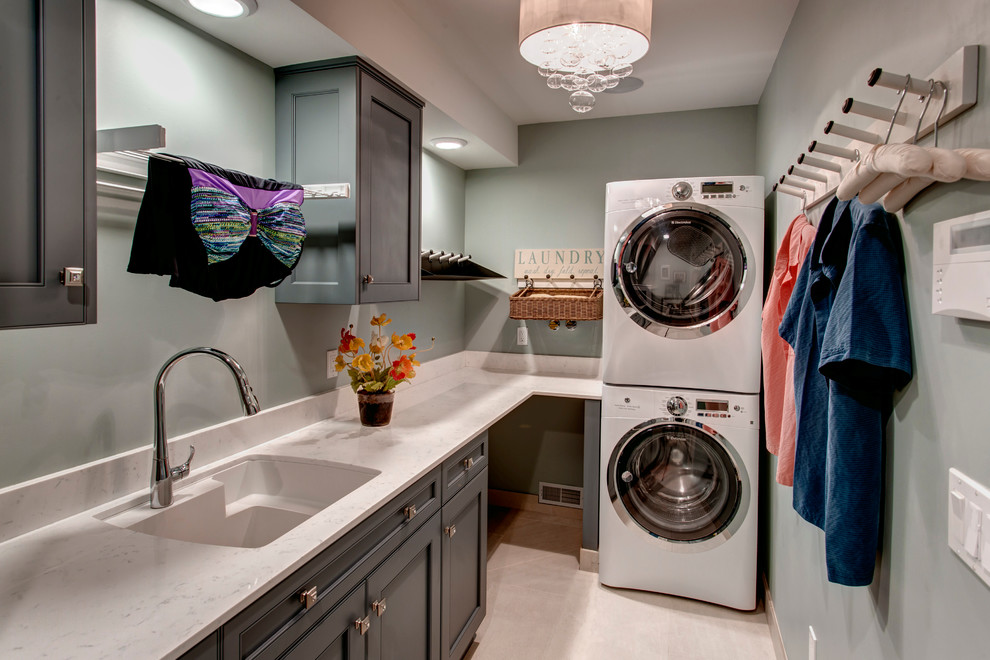 Photo of a medium sized classic galley separated utility room in Seattle with a submerged sink, shaker cabinets, engineered stone countertops, porcelain flooring, a stacked washer and dryer, grey cabinets and grey walls.