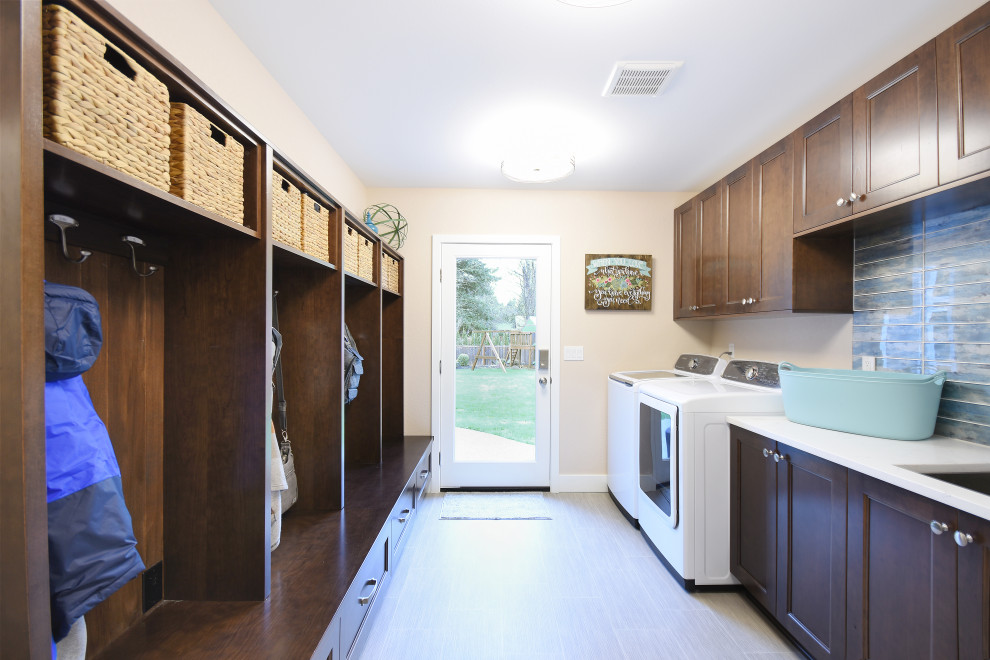 シアトルにあるトランジショナルスタイルのおしゃれな家事室 (I型、アンダーカウンターシンク、落し込みパネル扉のキャビネット、中間色木目調キャビネット、ベージュの壁、左右配置の洗濯機・乾燥機、ベージュの床、白いキッチンカウンター) の写真