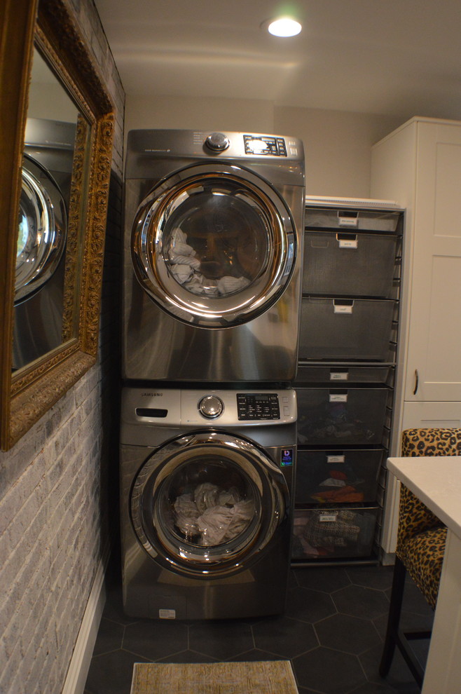 Modelo de lavadero ecléctico con armarios estilo shaker, puertas de armario blancas, encimera de acrílico, suelo de baldosas de cerámica, lavadora y secadora apiladas, suelo gris y encimeras grises