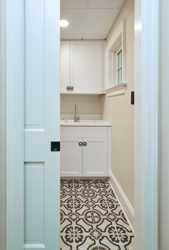 Design ideas for a medium sized country single-wall separated utility room in Philadelphia with an integrated sink, shaker cabinets, white cabinets, engineered stone countertops, beige walls, concrete flooring, a side by side washer and dryer and grey floors.