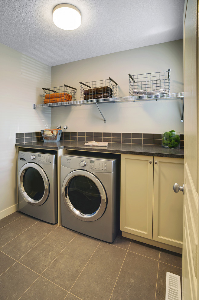 Inspiration for a classic utility room in Edmonton with recessed-panel cabinets, a side by side washer and dryer, grey floors and beige cabinets.