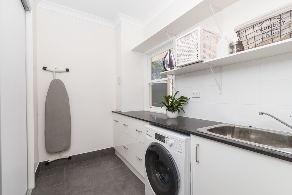 Photo of a contemporary single-wall separated utility room in Brisbane with a built-in sink, flat-panel cabinets, white cabinets, engineered stone countertops, white walls, ceramic flooring, a side by side washer and dryer and grey floors.