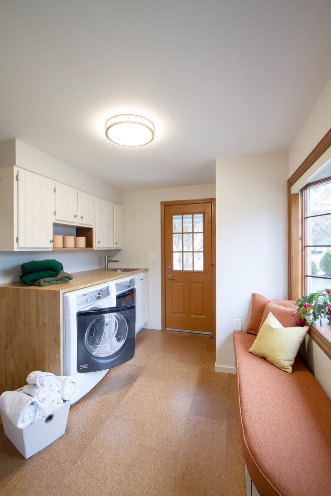 Example of a mid-sized transitional single-wall cork floor and brown floor utility room design in Philadelphia with an undermount sink, shaker cabinets, white cabinets, wood countertops, white walls, a side-by-side washer/dryer and beige countertops