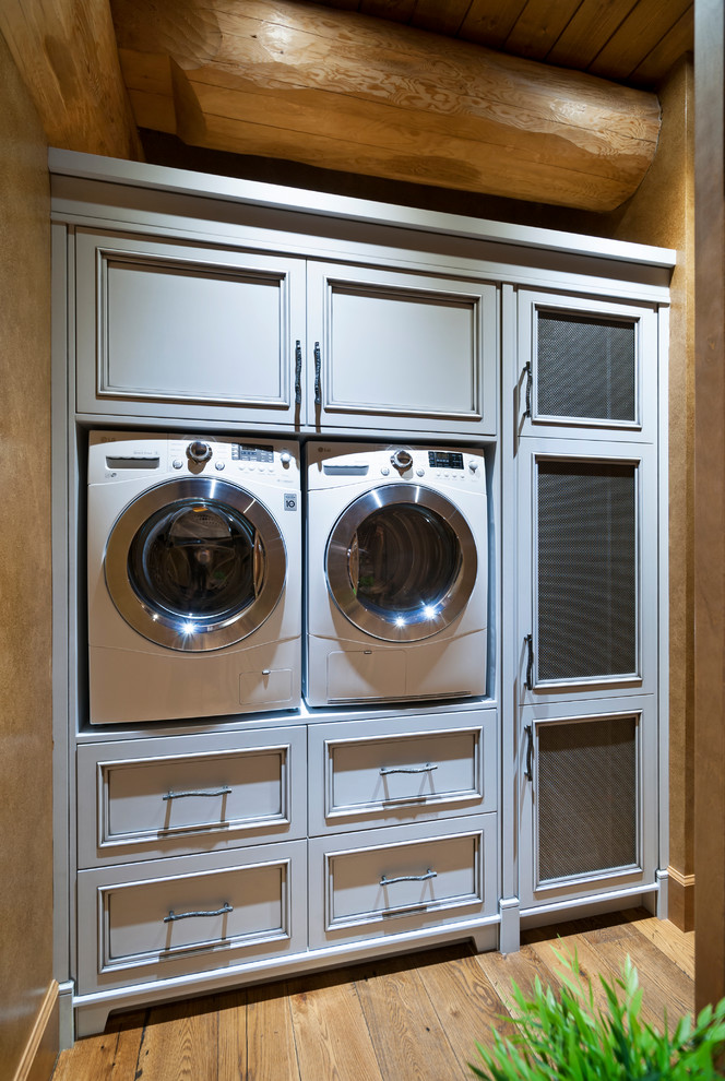 Idéer för mellanstora rustika linjära tvättstugor enbart för tvätt, med en tvättmaskin och torktumlare bredvid varandra, luckor med infälld panel, grå skåp, mellanmörkt trägolv och vitt golv