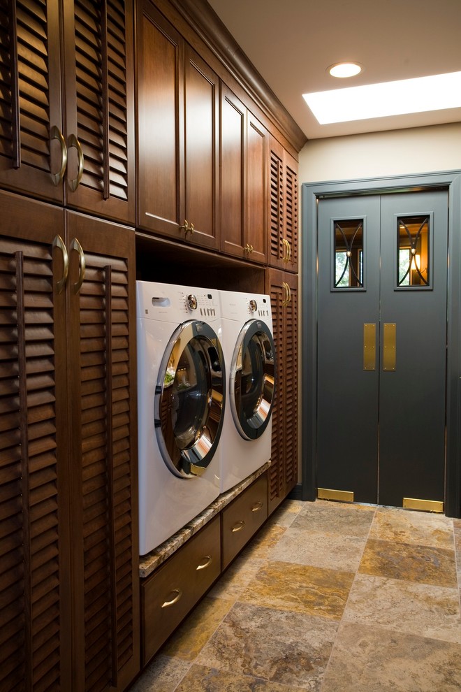 Modelo de cuarto de lavado clásico con armarios con puertas mallorquinas, puertas de armario de madera en tonos medios y lavadora y secadora juntas