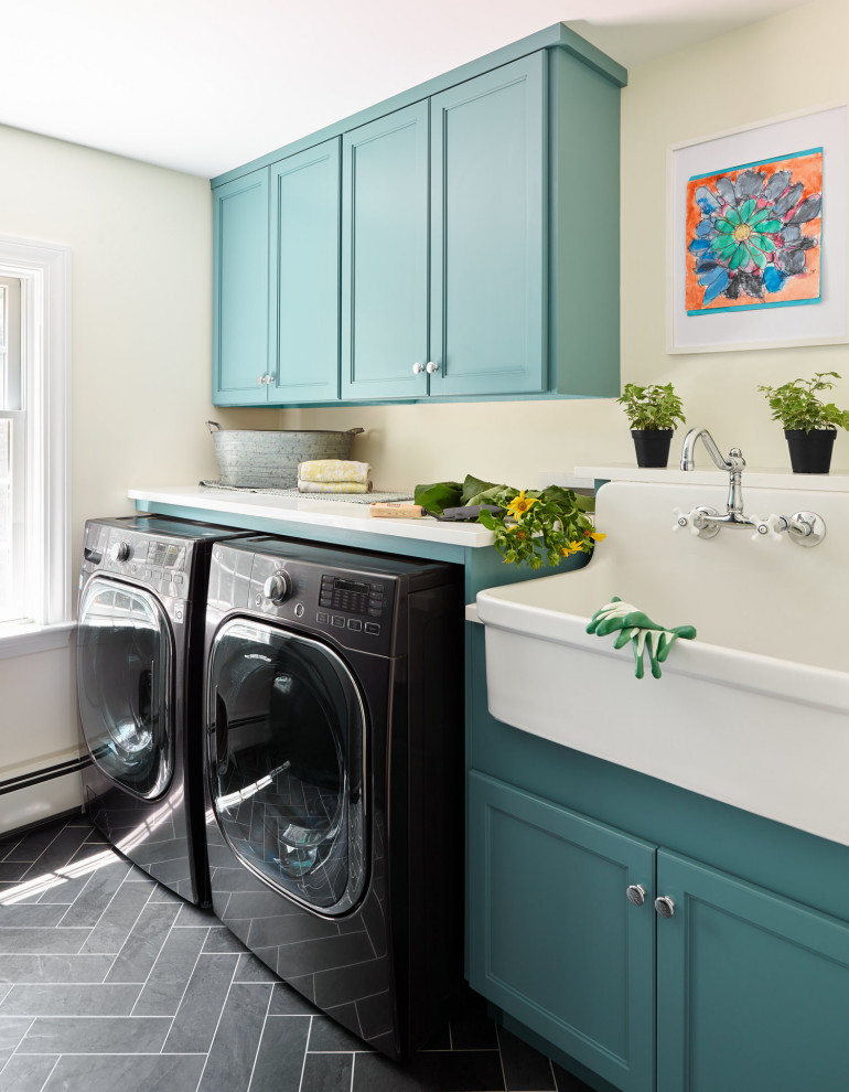 Example of a transitional gray floor laundry room design in Boston with a farmhouse sink, recessed-panel cabinets, turquoise cabinets, beige walls, a side-by-side washer/dryer and white countertops