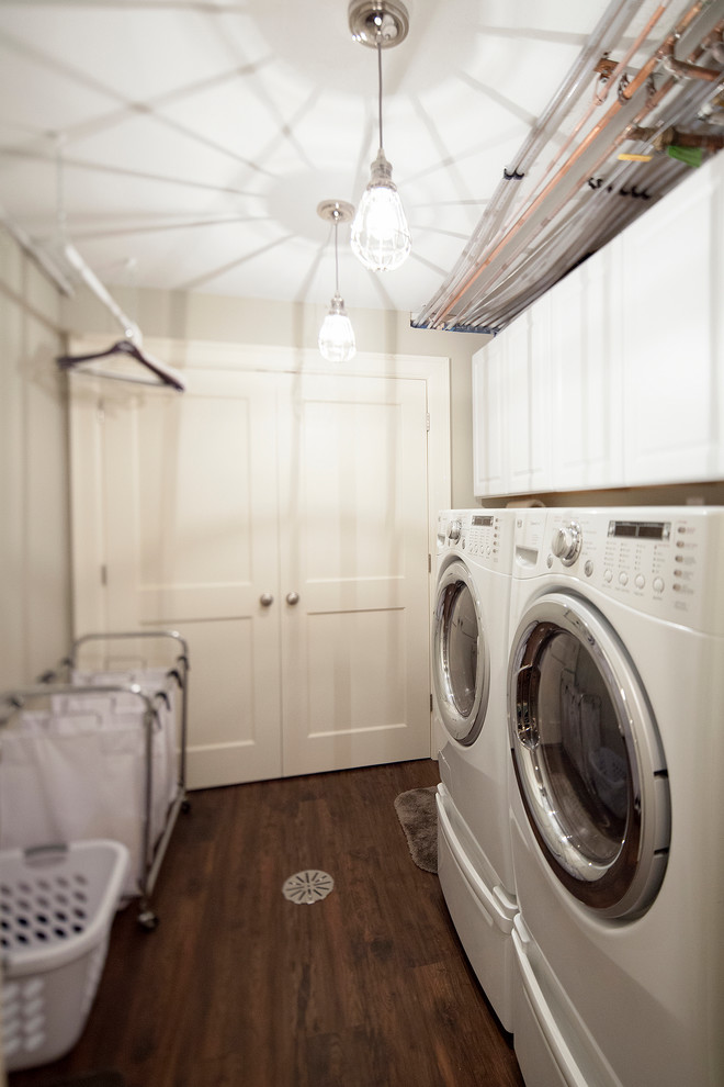 Foto på en vintage tvättstuga, med en enkel diskho, beige väggar, linoleumgolv och en tvättmaskin och torktumlare bredvid varandra
