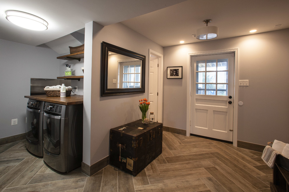 Immagine di una piccola lavanderia multiuso stile rurale con top in legno, pareti grigie, pavimento in gres porcellanato, lavatrice e asciugatrice affiancate e pavimento marrone