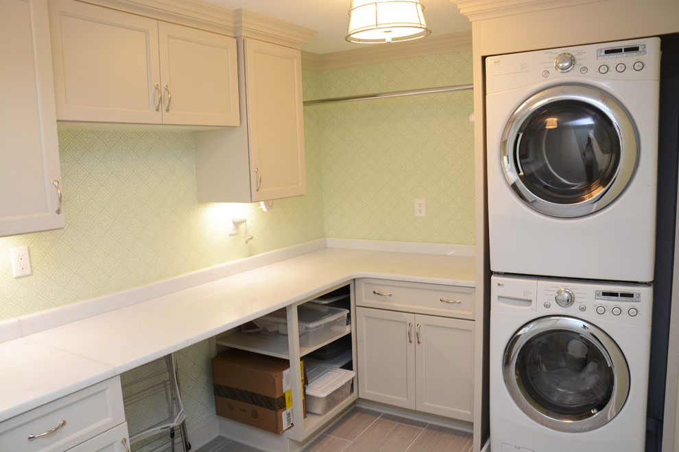 Inspiration for a large classic l-shaped utility room in DC Metro with a submerged sink, recessed-panel cabinets, grey cabinets, green walls, a stacked washer and dryer, grey floors and white worktops.