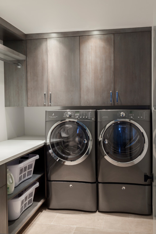 Dedicated laundry room - mid-sized contemporary l-shaped ceramic tile dedicated laundry room idea in New York with flat-panel cabinets, medium tone wood cabinets, solid surface countertops, white walls and a side-by-side washer/dryer