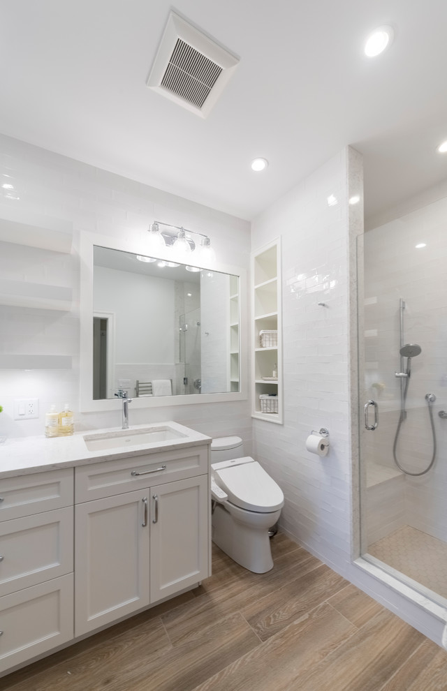 Inredning av ett klassiskt mellanstort badrum med dusch, med luckor med infälld panel, vita skåp, en dusch i en alkov, en bidé, vit kakel, tunnelbanekakel, vita väggar, klinkergolv i porslin, ett undermonterad handfat, bänkskiva i kvarts, brunt golv och dusch med gångjärnsdörr