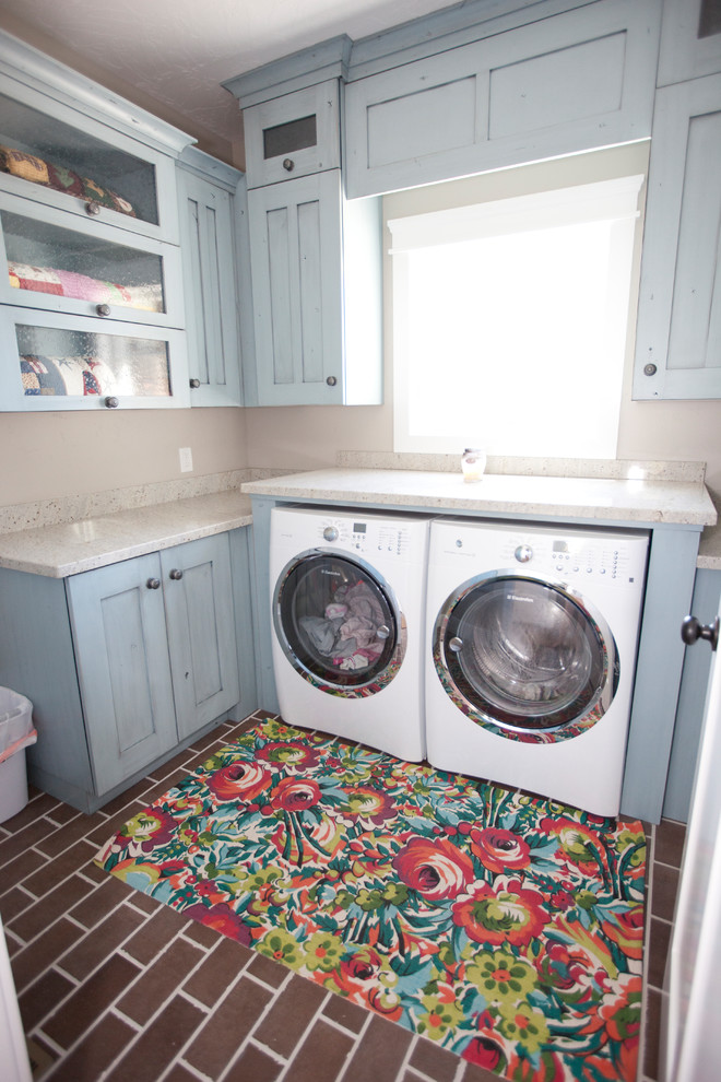 Foto di una sala lavanderia tradizionale di medie dimensioni con ante in stile shaker, ante blu, top in quarzite, pareti grigie, pavimento in mattoni, lavatrice e asciugatrice affiancate e pavimento marrone