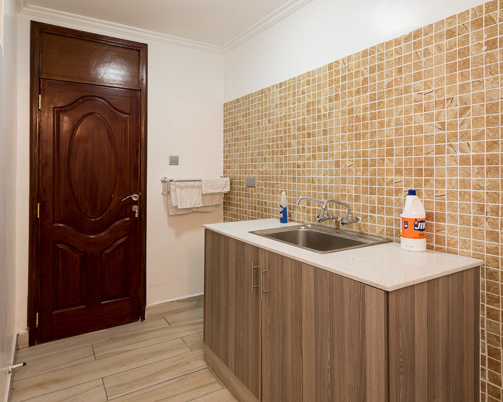 Small minimalist single-wall ceramic tile and brown floor utility room photo in Other with a drop-in sink, flat-panel cabinets, limestone countertops, white countertops, dark wood cabinets and white walls