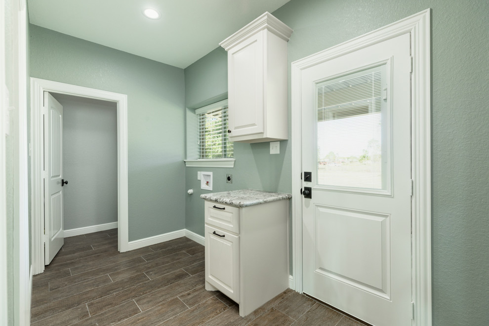 Medium sized rural single-wall utility room in Houston with raised-panel cabinets, white cabinets, granite worktops, grey walls, ceramic flooring, a side by side washer and dryer, brown floors and brown worktops.