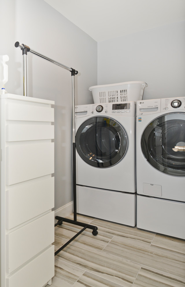 Esempio di un ripostiglio-lavanderia moderno di medie dimensioni con pareti grigie, lavatrice e asciugatrice affiancate e pavimento grigio