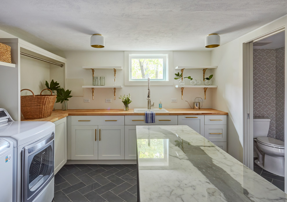 This is an example of a large classic l-shaped separated utility room in Chicago with a built-in sink, shaker cabinets, white cabinets, wood worktops, white walls, slate flooring, a side by side washer and dryer, grey floors and brown worktops.