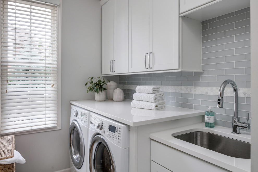 Exempel på en mellanstor klassisk grå linjär grått tvättstuga enbart för tvätt, med en undermonterad diskho, skåp i shakerstil, vita skåp, bänkskiva i kvarts, grå väggar och en tvättmaskin och torktumlare bredvid varandra