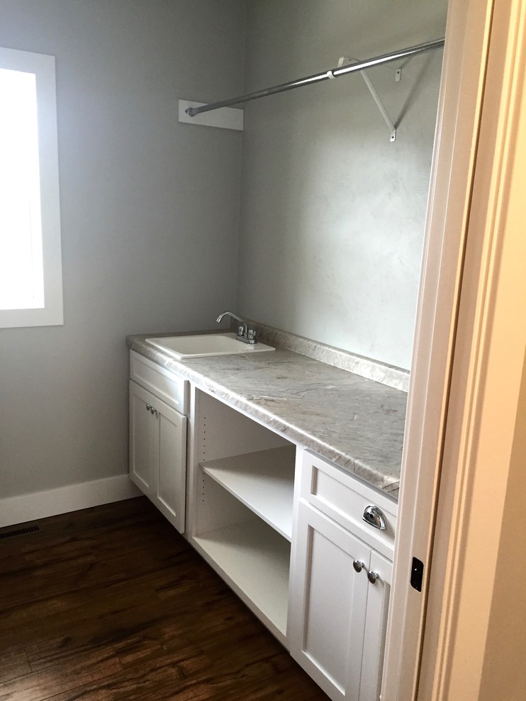 Example of a mid-sized arts and crafts u-shaped medium tone wood floor dedicated laundry room design in Other with a drop-in sink, shaker cabinets, white cabinets, laminate countertops, gray walls and a side-by-side washer/dryer