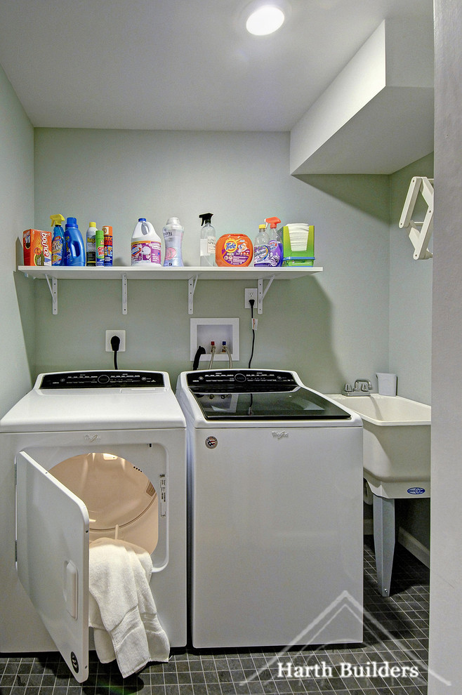 Bild på en liten vintage linjär tvättstuga enbart för tvätt, med en allbänk, grå väggar, klinkergolv i porslin, en tvättmaskin och torktumlare bredvid varandra och grått golv