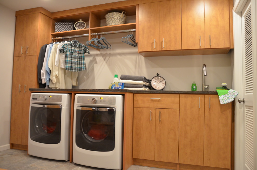 ワシントンD.C.にあるお手頃価格の中くらいなトラディショナルスタイルのおしゃれな家事室 (ll型、アンダーカウンターシンク、フラットパネル扉のキャビネット、中間色木目調キャビネット、グレーの壁、左右配置の洗濯機・乾燥機) の写真