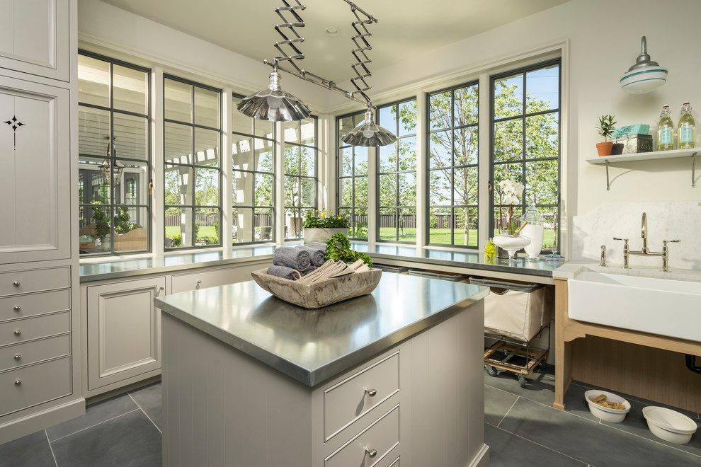 Dedicated laundry room - traditional l-shaped dedicated laundry room idea in Salt Lake City with a farmhouse sink, gray cabinets, white walls and recessed-panel cabinets