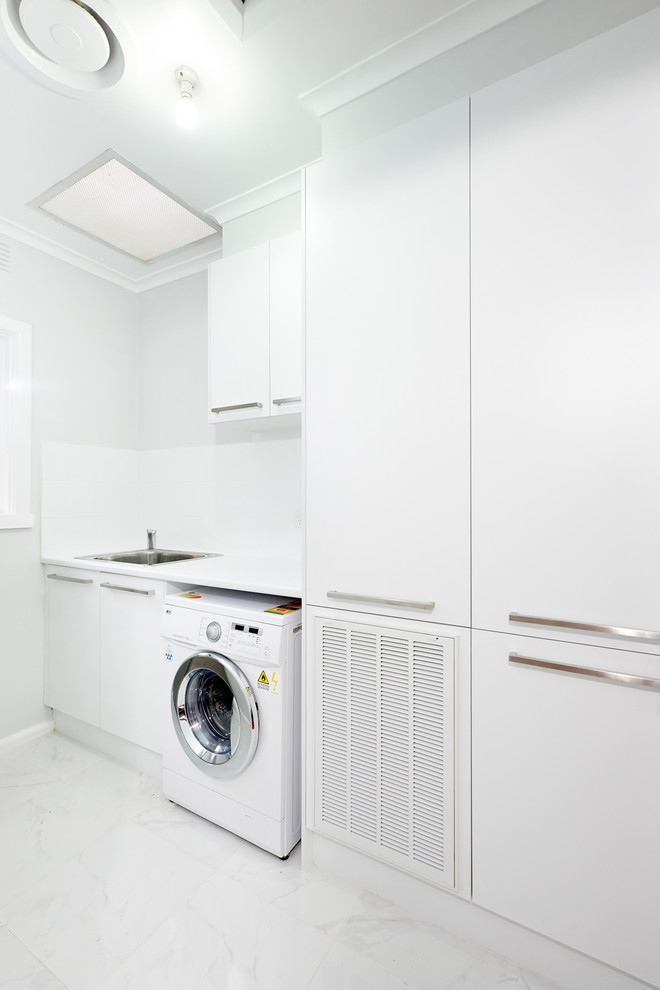Idee per una sala lavanderia minimalista con lavello da incasso, ante lisce, ante bianche e pareti bianche