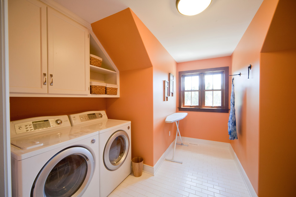 Classic utility room in Other with orange walls and white cabinets.