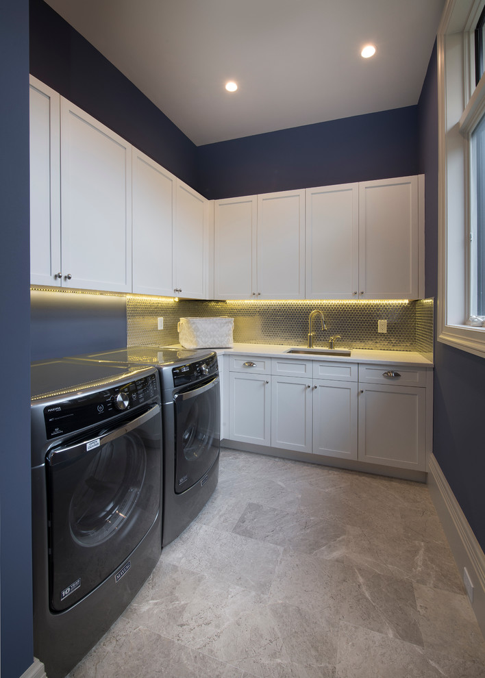 Exempel på en stor modern parallell tvättstuga enbart för tvätt, med en undermonterad diskho, skåp i shakerstil, vita skåp, blå väggar och en tvättmaskin och torktumlare bredvid varandra