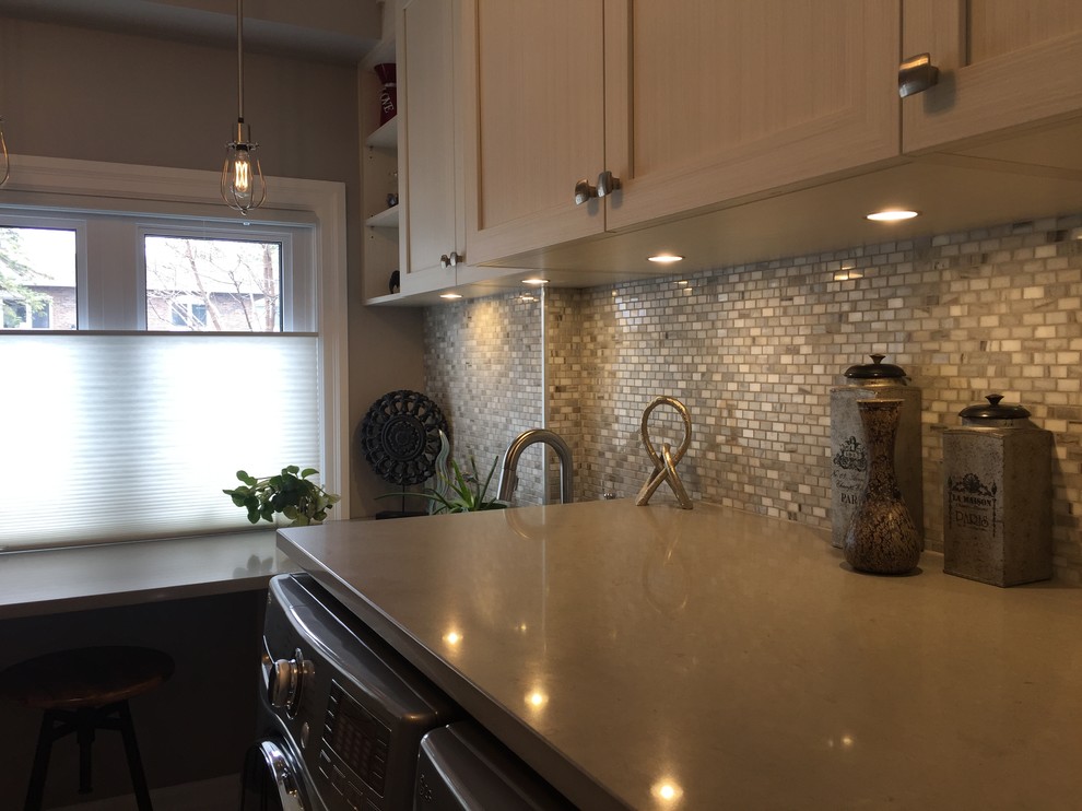 Example of a mid-sized transitional l-shaped porcelain tile and gray floor utility room design in Montreal with an undermount sink, shaker cabinets, beige cabinets, quartz countertops, gray walls, a side-by-side washer/dryer and beige countertops
