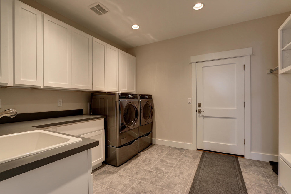 Example of a large arts and crafts u-shaped ceramic tile dedicated laundry room design in Denver with a drop-in sink, shaker cabinets, white cabinets, solid surface countertops, beige walls and a side-by-side washer/dryer