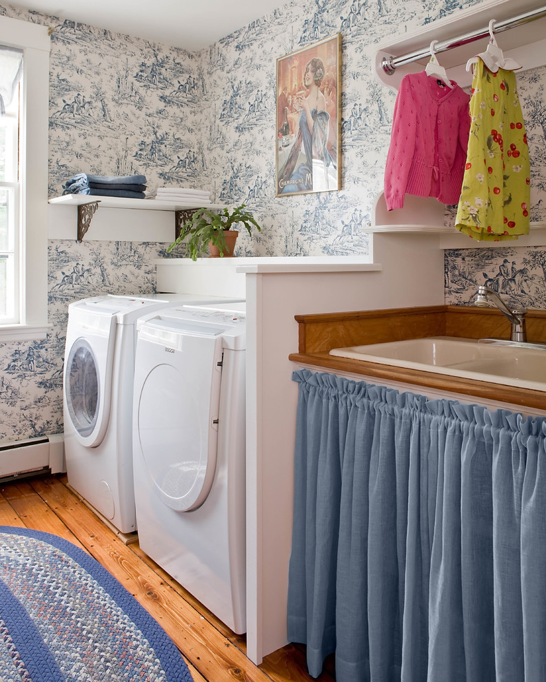 Klassische Waschküche mit Waschmaschine und Trockner nebeneinander, Einbauwaschbecken, offenen Schränken, bunten Wänden und braunem Holzboden in Boston