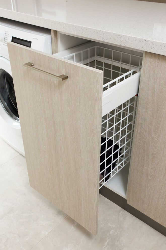 Ejemplo de lavadero moderno con armarios con paneles lisos, puertas de armario de madera clara, encimera de cuarzo compacto y encimeras blancas
