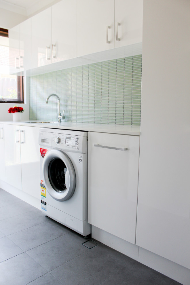 Inspiration för små moderna linjära vitt tvättstugor enbart för tvätt och med garderob, med en nedsänkt diskho, släta luckor, vita skåp, bänkskiva i kvarts, gröna väggar, klinkergolv i porslin och grått golv