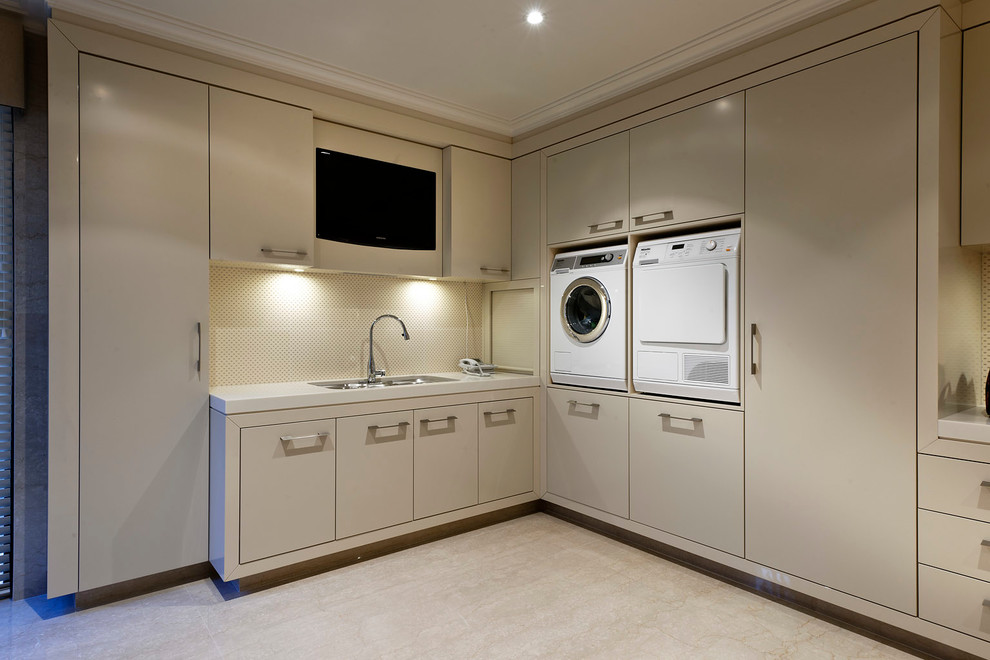 Idéer för en modern tvättstuga, med släta luckor, beige skåp, beige väggar, en tvättmaskin och torktumlare bredvid varandra och beiget golv