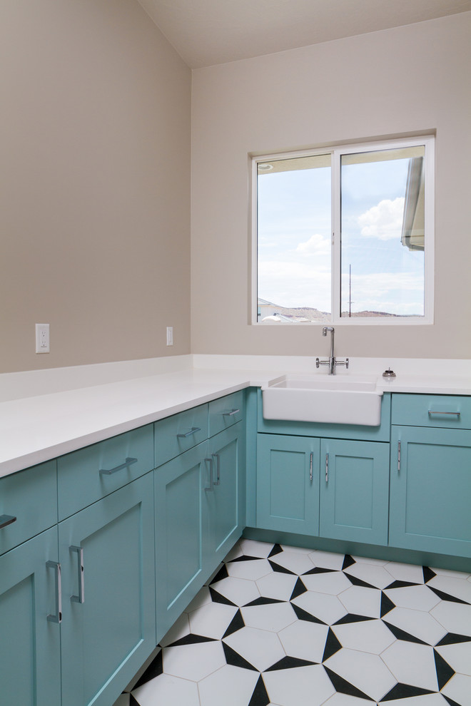 Mid-sized trendy l-shaped ceramic tile and multicolored floor dedicated laundry room photo in Austin with a farmhouse sink, recessed-panel cabinets, blue cabinets, quartz countertops, gray walls and white countertops