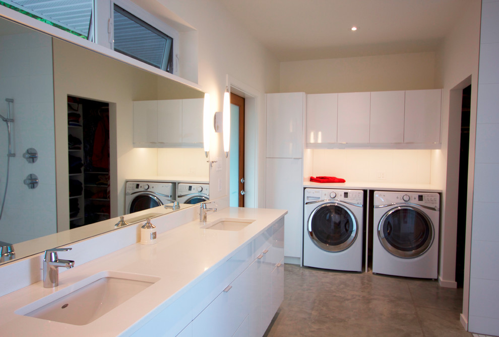 Example of a mid-sized minimalist single-wall concrete floor and gray floor utility room design in Other with an undermount sink, flat-panel cabinets, white cabinets, quartz countertops, white walls, a side-by-side washer/dryer and white countertops