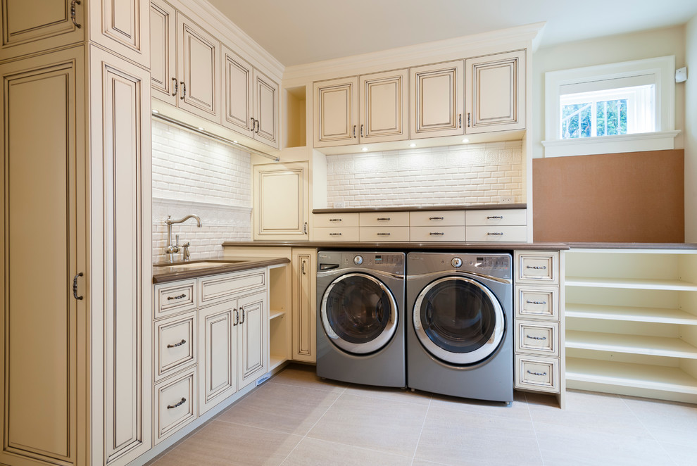 Inspiration for a traditional l-shaped separated utility room in Vancouver with a submerged sink, raised-panel cabinets, engineered stone countertops, white walls, porcelain flooring, a side by side washer and dryer and beige cabinets.