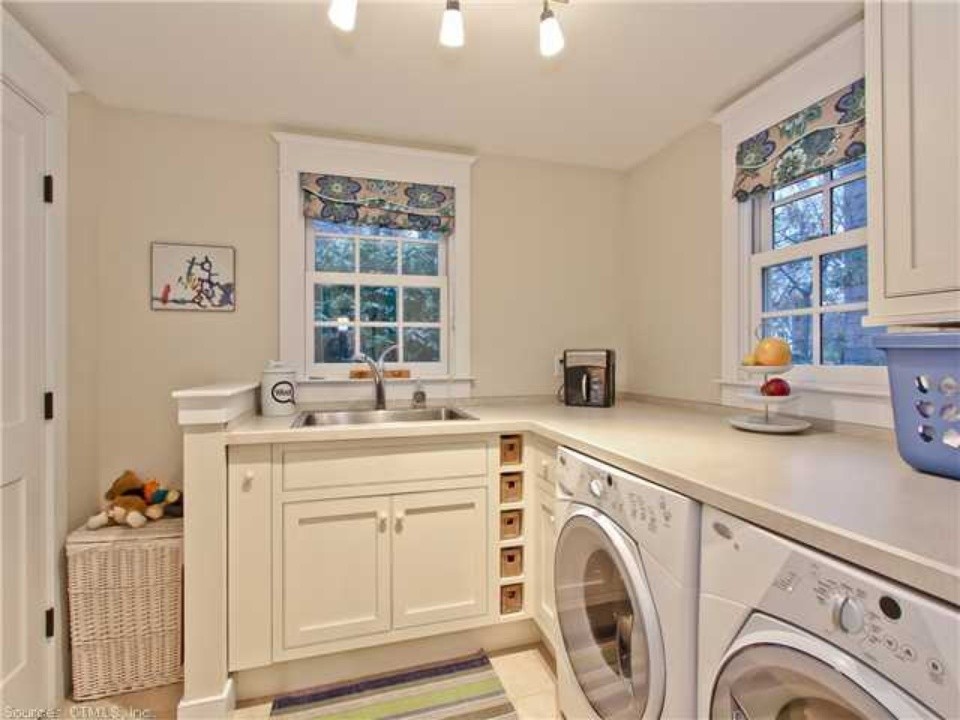 Inspiration for a small farmhouse l-shaped light wood floor dedicated laundry room remodel in New York with a drop-in sink, flat-panel cabinets, white cabinets, laminate countertops, a side-by-side washer/dryer and beige walls