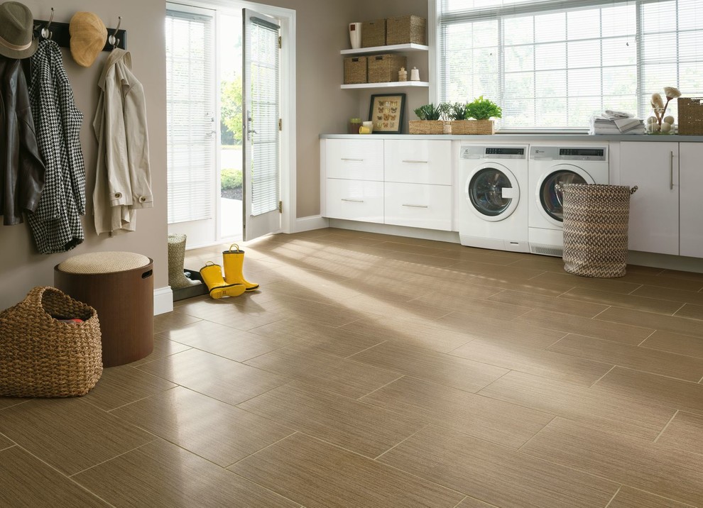 Exempel på en stor klassisk grå linjär grått tvättstuga enbart för tvätt, med vita skåp, laminatgolv, en tvättmaskin och torktumlare bredvid varandra, släta luckor, bänkskiva i betong, beige väggar och beiget golv