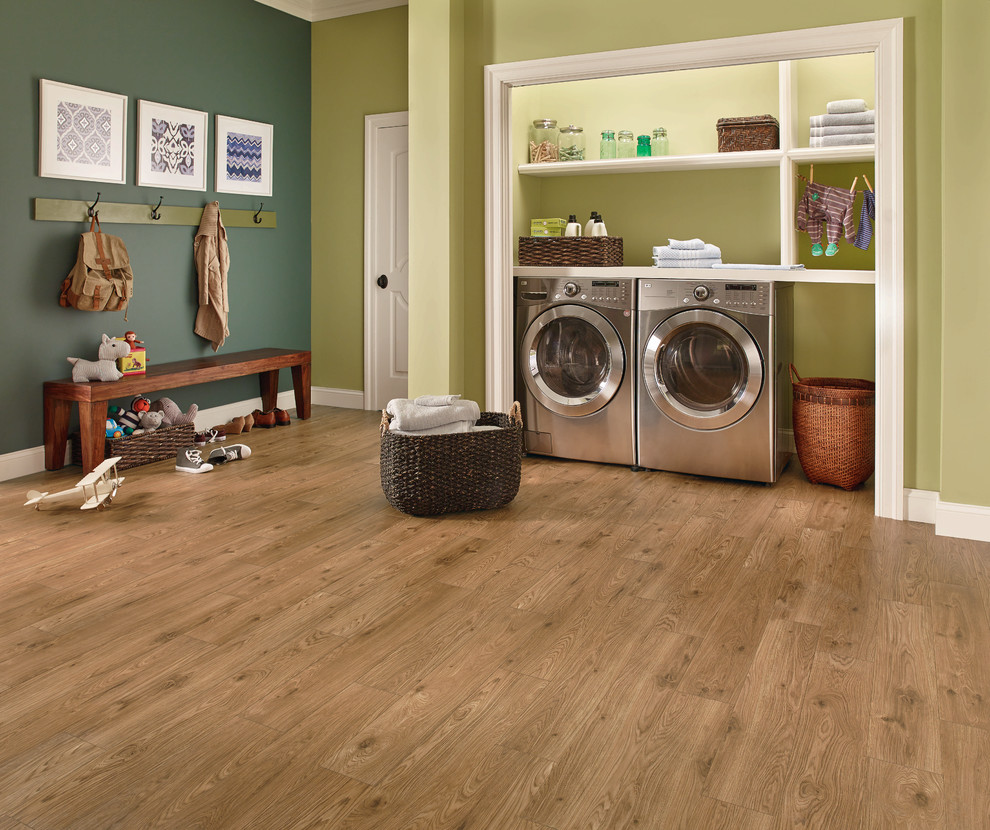 Ejemplo de lavadero multiusos y lineal tradicional renovado grande con paredes verdes, suelo de madera en tonos medios, lavadora y secadora juntas y suelo marrón