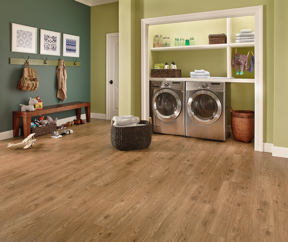 Foto di un ripostiglio-lavanderia tradizionale di medie dimensioni con pareti verdi, pavimento in legno massello medio, lavatrice e asciugatrice affiancate e pavimento marrone