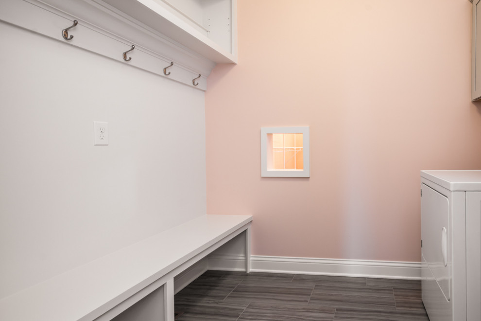 Свежая идея для дизайна: прямая универсальная комната в стиле неоклассика (современная классика) с белыми фасадами, розовыми стенами, полом из винила, со стиральной и сушильной машиной рядом и серым полом - отличное фото интерьера