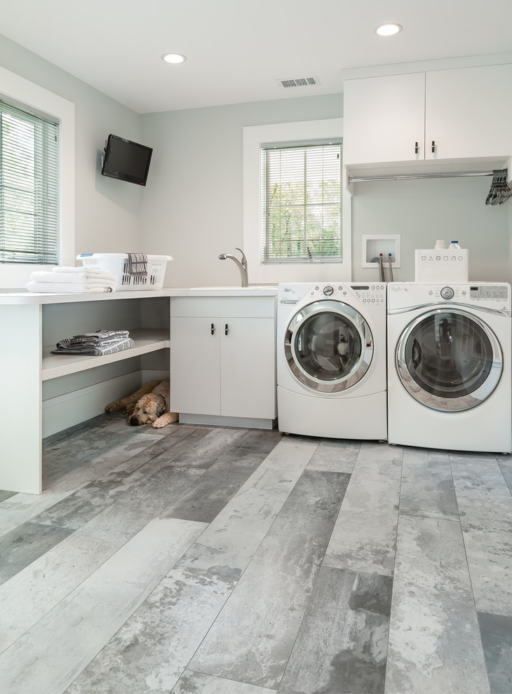 Laundry room - contemporary l-shaped laundry room idea in New York with flat-panel cabinets, white cabinets, a drop-in sink and gray walls