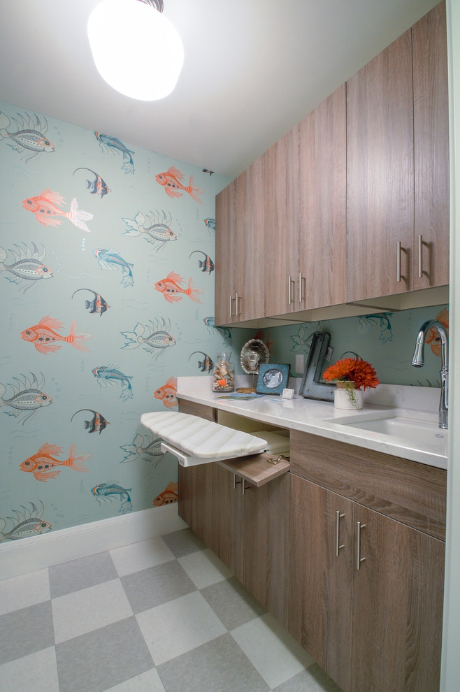 This is an example of a medium sized nautical galley separated utility room in Minneapolis with a submerged sink, flat-panel cabinets, marble worktops, blue walls, lino flooring, a stacked washer and dryer and medium wood cabinets.