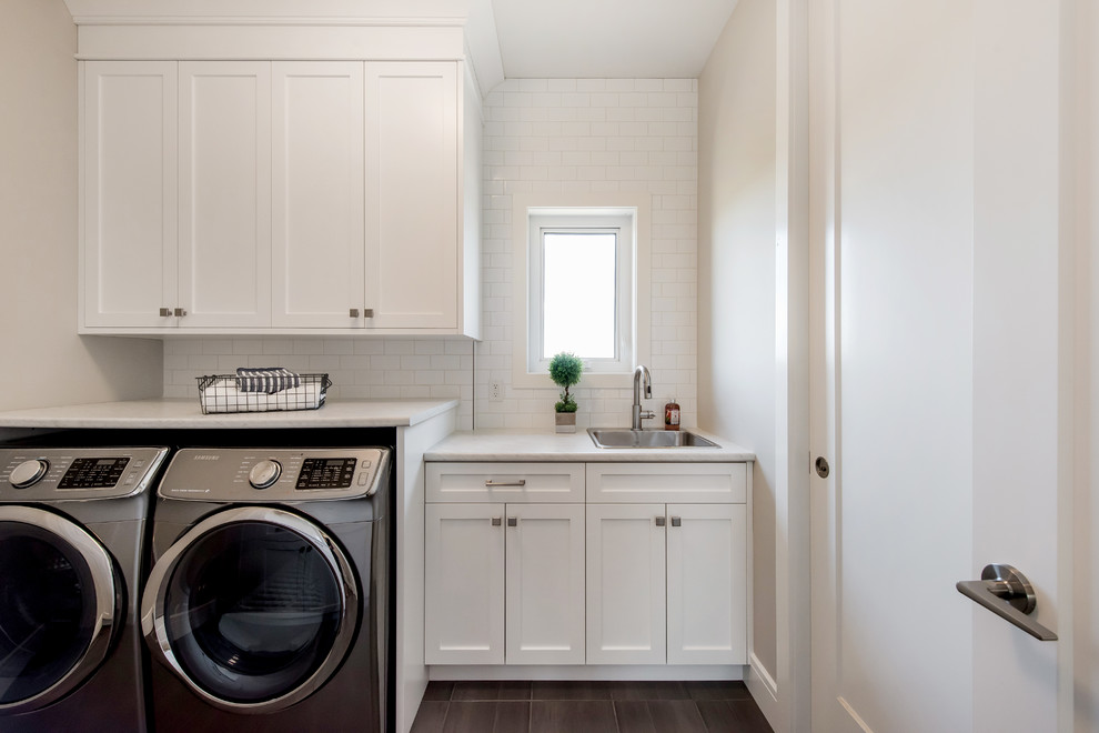 Dedicated laundry room - mid-sized traditional galley ceramic tile and gray floor dedicated laundry room idea in Other with a single-bowl sink, shaker cabinets, white cabinets, laminate countertops, beige walls, a side-by-side washer/dryer and white countertops