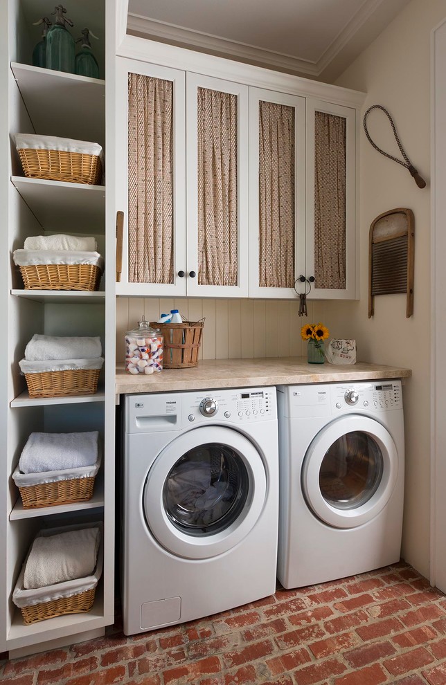 Imagen de lavadero campestre con armarios con paneles empotrados, puertas de armario blancas, paredes beige, suelo de ladrillo, lavadora y secadora juntas, suelo rojo y encimeras beige
