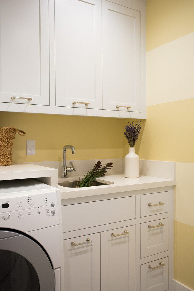 Idéer för en mellanstor klassisk linjär tvättstuga enbart för tvätt, med en undermonterad diskho, skåp i shakerstil, vita skåp, bänkskiva i kvarts, gula väggar, marmorgolv och en tvättmaskin och torktumlare bredvid varandra