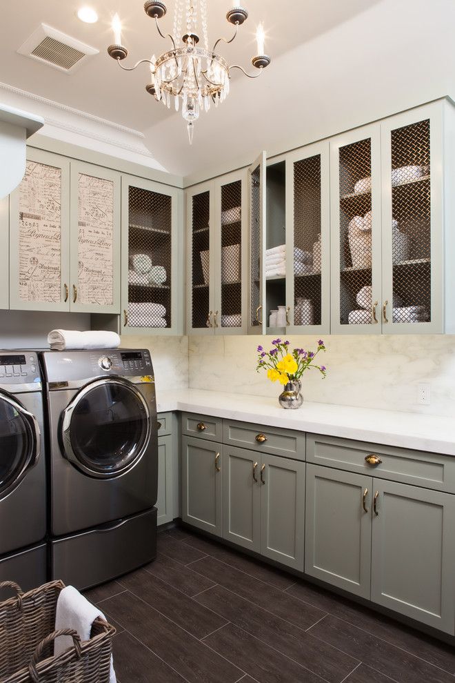 Modelo de lavadero en L tradicional con armarios estilo shaker, puertas de armario verdes, lavadora y secadora juntas, suelo marrón y encimeras blancas